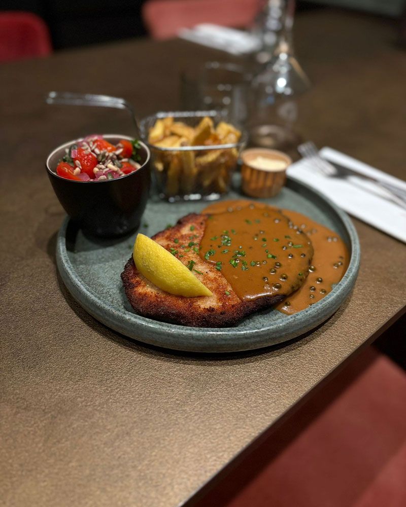 Bord met een schnitzel, garnituur, saus frites en mayonaise